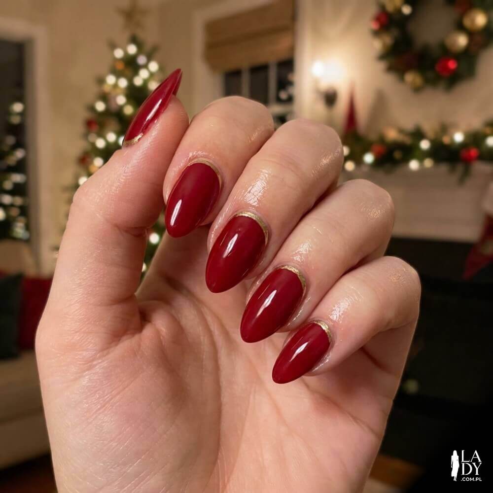Nowoczesne czerwone paznokcie ze złotym łukiem przy skórkach w stylu odwróconego frencha