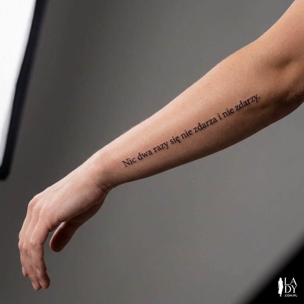 Tatuaż z cytatem „Nic dwa razy się nie zdarza i nie zdarzy.” na wewnętrznym przedramieniu kobiety