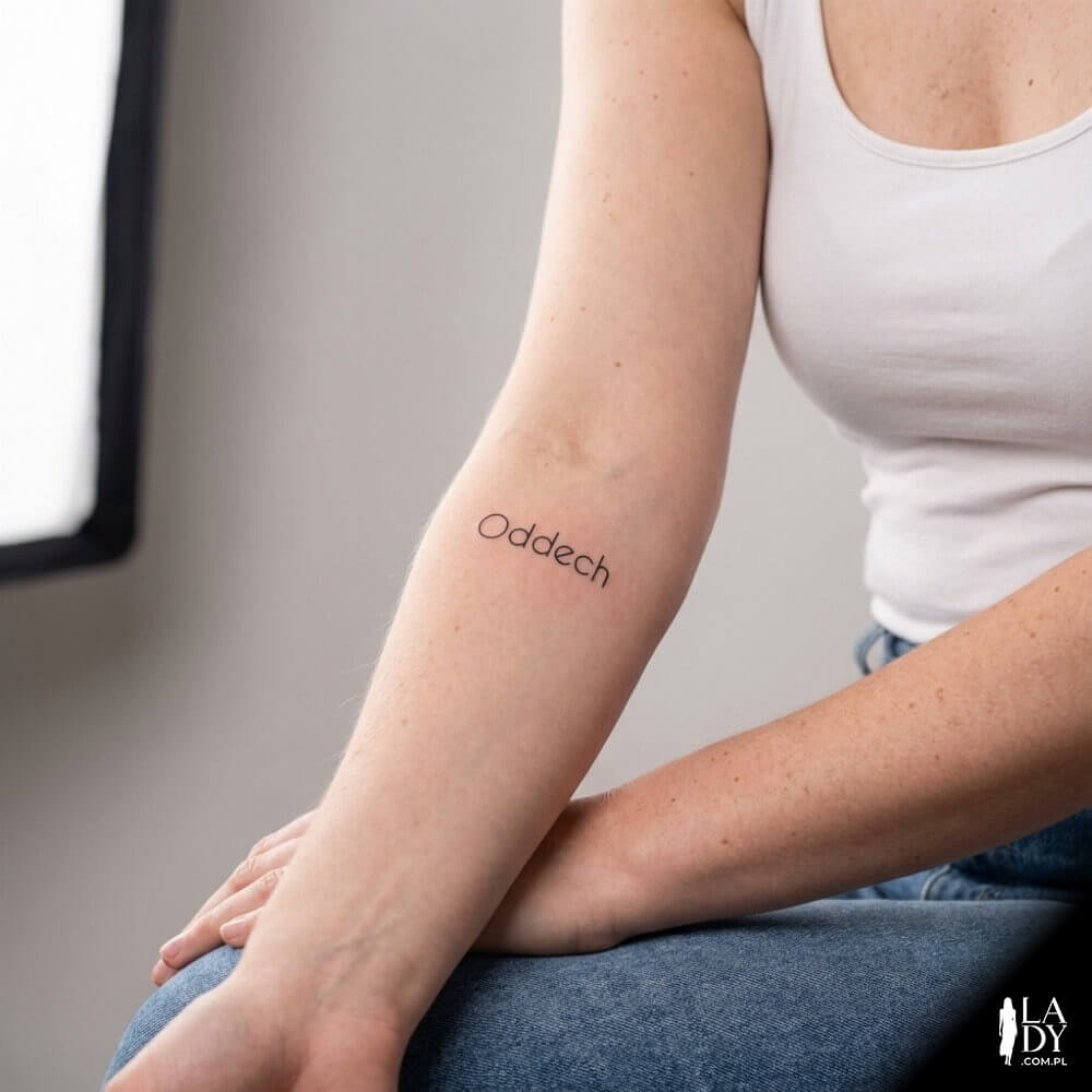 Tatuaż „Oddech” na wewnętrznej stronie nadgarstka kobiety w studyjnym świetle