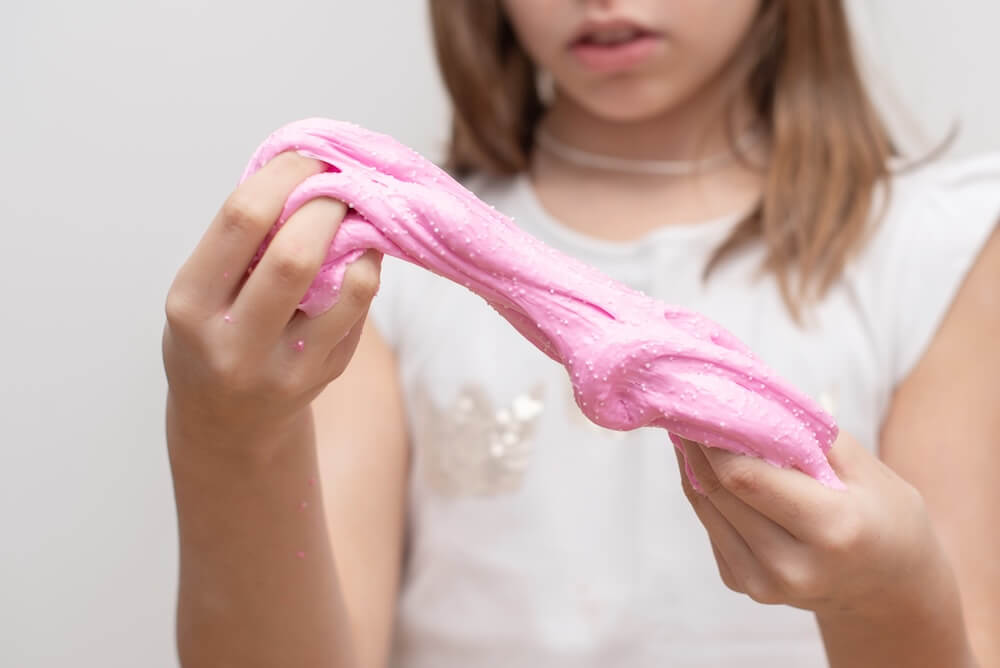 Dziewczynka z różowym slimem w rękach