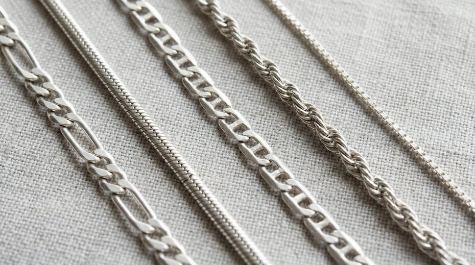 Zbliżenie na różne typy plecenia łańcuszków srebrnych rozłożone obok siebie