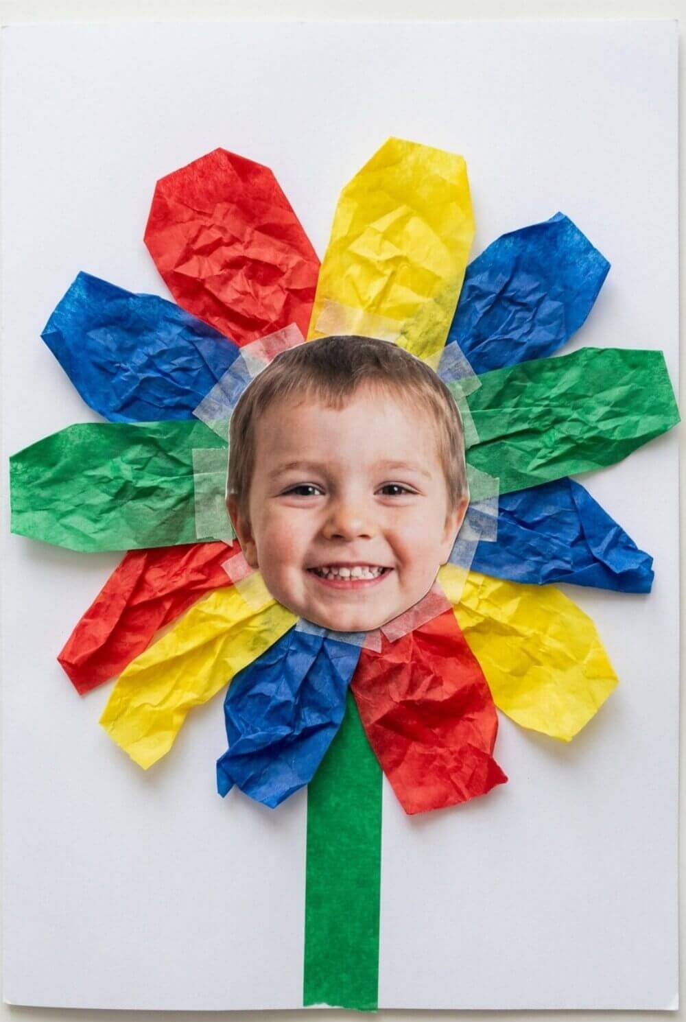 Papierowy kwiatek na laurce ze zdjęciem twarzy dziecka w środku