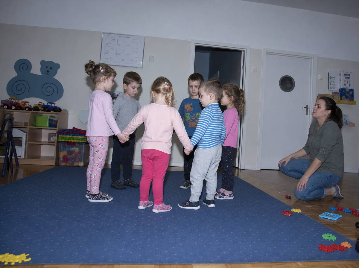 Dzieci ustawione w kręgu w sali przedszkolnej podczas zabawy ruchowej dopasowanej do wieku grupy