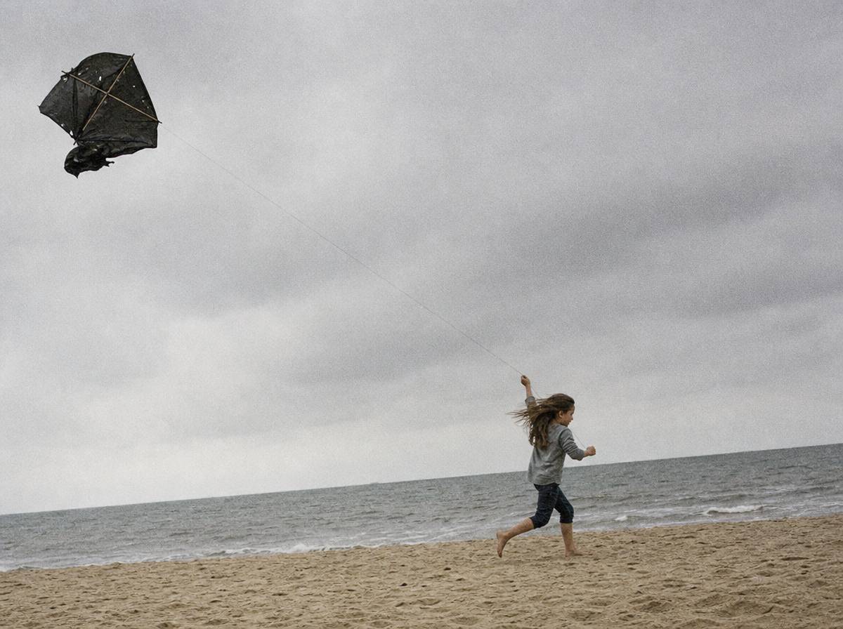 Dziecko puszcza domowy latawiec z worka na śmieci na plaży