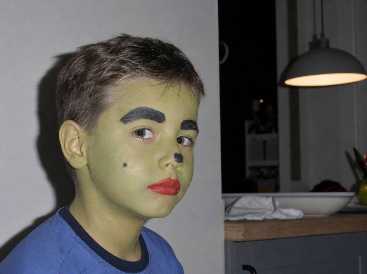 Dziecko z klasycznym zielonym makijażem czarownicy na Halloween